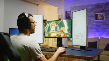 Zaferi için heyecanlanan genç adam çevrimiçi bir tetikçiyi izlerken kulaklık takıyor.