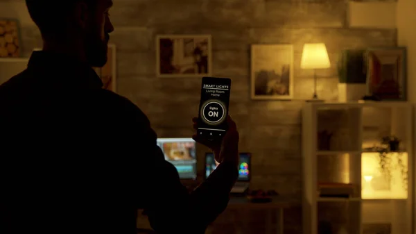 Man using a smart lights app to turn on the lights in the living room