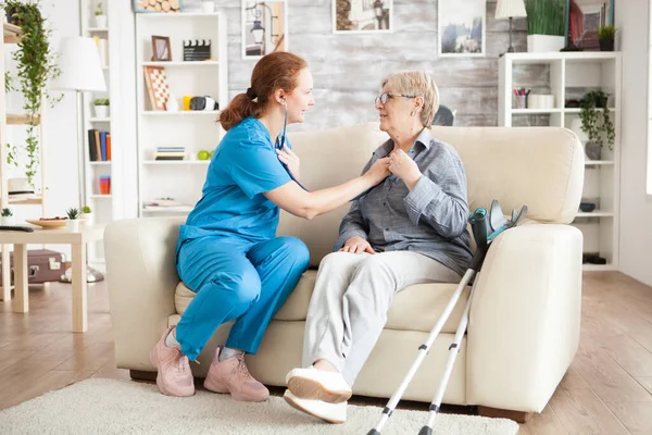 Enfermera sentada en un sofá con una anciana — Foto de Stock