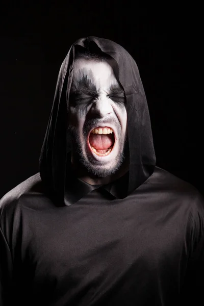 Портрет мрачного жнеца, кричащего на черном фоне — стоковое фото