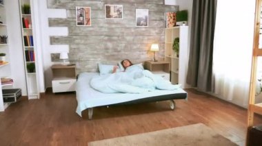 Pijamalı beyaz kadın uyanıyor.