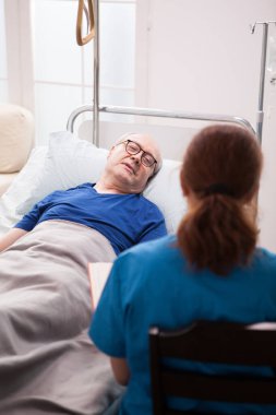 Hemşirenin sandalyeye oturup emeklilerle konuşması.