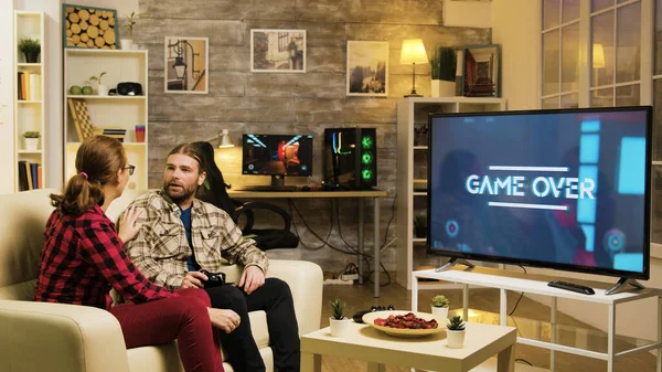 Девушка указывает на экран телевизора, пока парень играет в видеоигры — стоковое фото