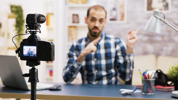 Vlogger sitting at desk in living room talking and looking at the camera — Stock Photo, Image