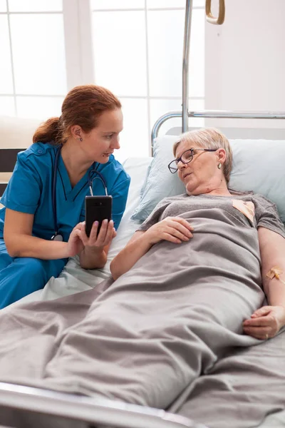 Vrouwelijke verzorger in verpleeghuis praten met oude vrouw — Stockfoto