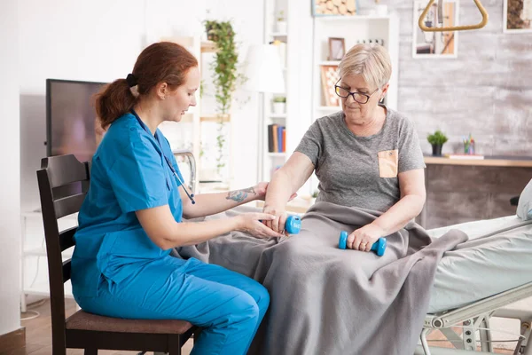 Femme âgée assise sur le lit dans une maison de soins infirmiers faisant de la physiothérapie — Photo