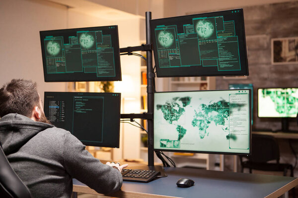 Мужчина-хакер смотрит на несколько экранов для кражи данных
