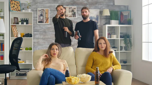 Vänner i vardagsrummet äter chips och talar om matchen på tv — Stockfoto