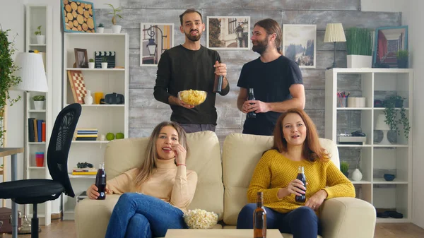 Flickor som sitter på soffan och äter popcorn medan de tittar på tv — Stockfoto