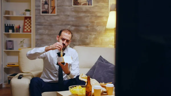 Homme d'affaires avec cravate manger des nouilles assis sur le canapé — Photo