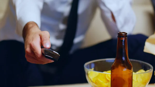 Primer plano del hombre de negocios sentado en el sofá usando control remoto —  Fotos de Stock