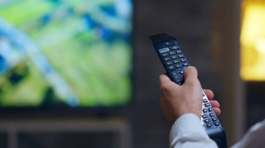 Back view of entrepreneur switching tv programs