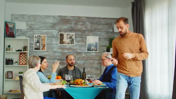 Bakåt bild av ung man som använder smartphone för att ta ett gruppfoto — Stockvideo