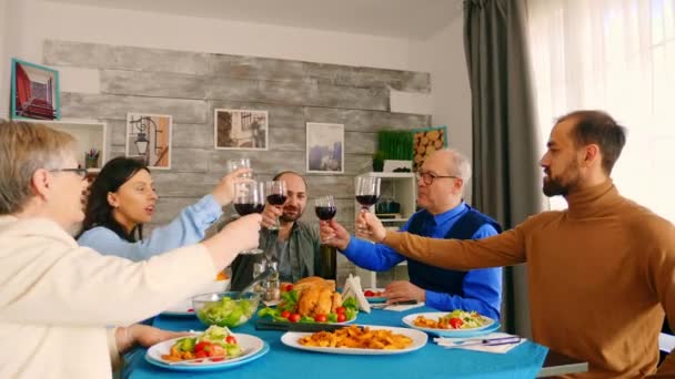 Fiatalember csörömpöl egy pohár bort a családjával. — Stock videók