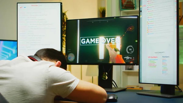 Young man taking his headphones down after losing at shooter game — Stock Photo, Image