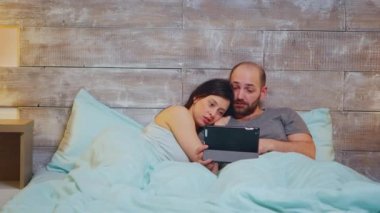 Pijamalı beyaz bir çift yatakta yatıyor.