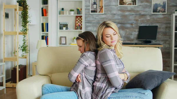 Little girl with bad behavior sitting back to back with her mother