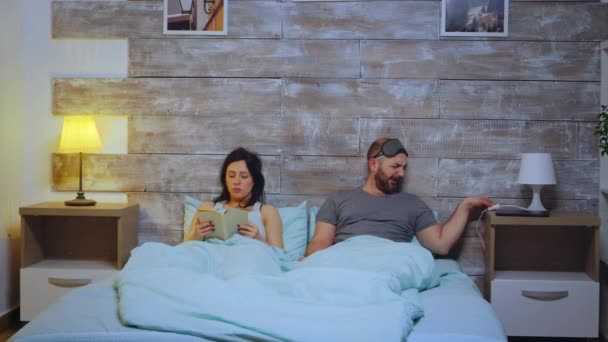 Женщина читает книгу в пижаме в спальне — стоковое видео