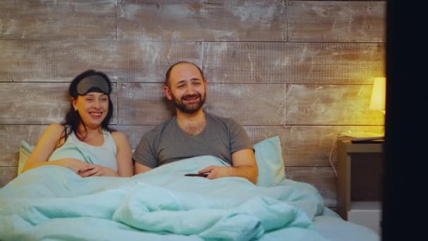 Забавная пара смотрит телевизор в спальне — стоковое видео