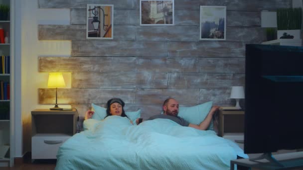 Молодая пара под простынями в своей спальне — стоковое видео