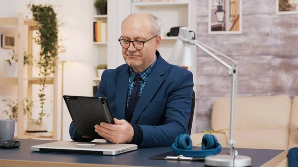Elederly man using tablet while sitting down at the office — Stock Photo, Image