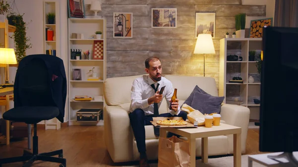 Uomo d'affari con cravatta mangiare pizza e guardare la tv — Foto Stock
