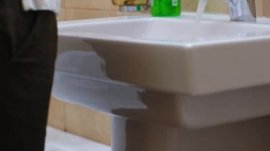 Beyaz kadın musluğun altında ellerini yıkıyor.