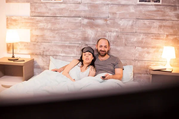 Jovem casal de pijama assistindo tv — Fotografia de Stock