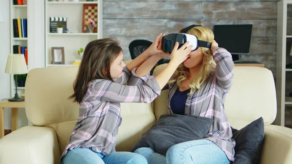 Küçük kız, güzel annesine sanal gerçeklik kulaklığını nasıl kullandığını gösteriyor. — Stok fotoğraf