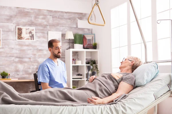 Médico varón hablando con una anciana jubilada en un asilo de ancianos —  Fotos de Stock