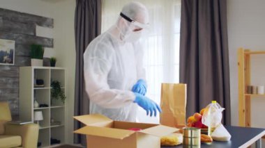 Koruyucu giysili adam yiyecek paketliyor.