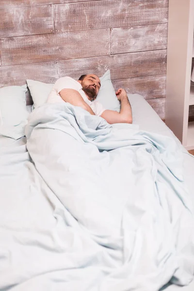 Unavený muž odpočívá ve své pohodlné posteli — Stock fotografie