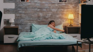 Güzel sarışın kadın sıcak oturma odasındaki gece lambasını söndürüyor.