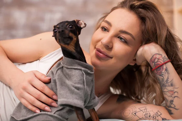 Bella giovane donna in pigiama a giocare con il suo cane — Foto Stock