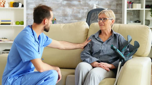 Male nurse talking with old woman suffering of parkinson