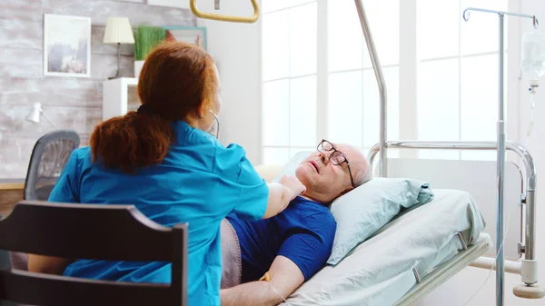 Velho doente em uma cama de hospital recebe seu batimento cardíaco verificado — Fotografia de Stock