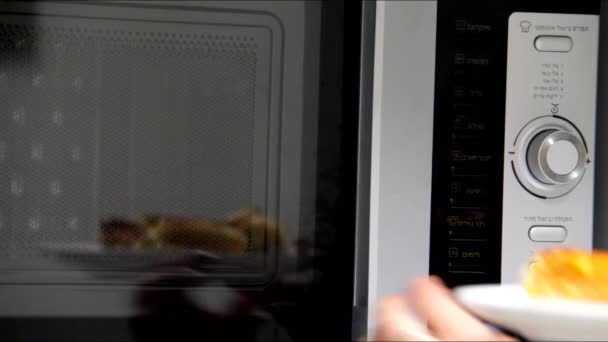 Молодая женщина нагревает еду в микроволновой печи — стоковое видео