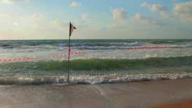 Siyah bayrak ve çizgili kırmızı kurdele sahilde