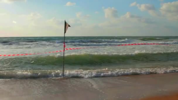 Black Flag en gestreept rood lint op het strand — Stockvideo