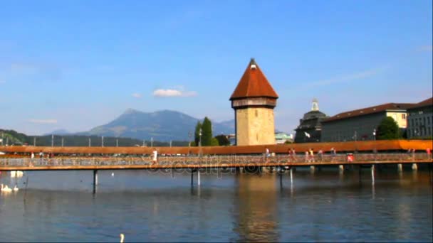 Frente al río Reuss Con vistas al famoso puente de madera de la capilla y la torre de agua en Luzern, Suiza — Vídeo de stock