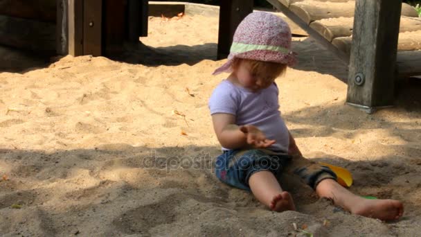 Kleine zwei-jährige süße Mädchen am heißen Tag spielen im Sandkasten — Stockvideo