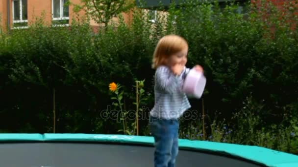 Kleines süßes blondes Mädchen am Sommertag auf dem großen Trampolin — Stockvideo