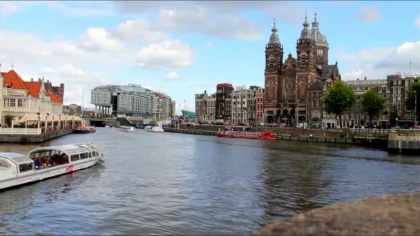 Blick auf die Nikolaikirche und die Häuser auf der anderen Seite des Amstel-Flusses im Sonnenuntergang. Amsterdam — Stockvideo