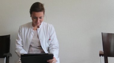 Hastanede bekleme odasında bir Tablet ile genç kadın doktor çalışma