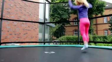 Küçük kız özel evin bahçesinde trambolin, atlama