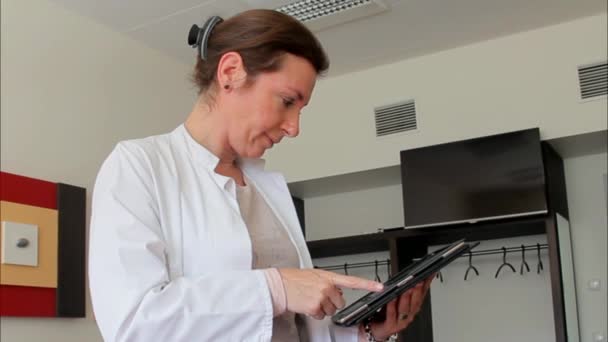 Jovem doutora trabalhando com um tablet na sala de espera do hospital — Vídeo de Stock