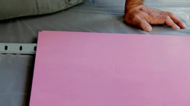 Ahşap bir yüzeye vernikli boya uygulayan bir fırça tutan el.