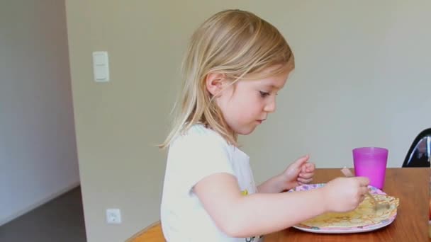 Niña comiendo panqueques y bebiendo leche en casa — Vídeos de Stock