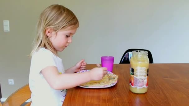 Kleines Mädchen isst Pfannkuchen und trinkt zu Hause Milch — Stockvideo