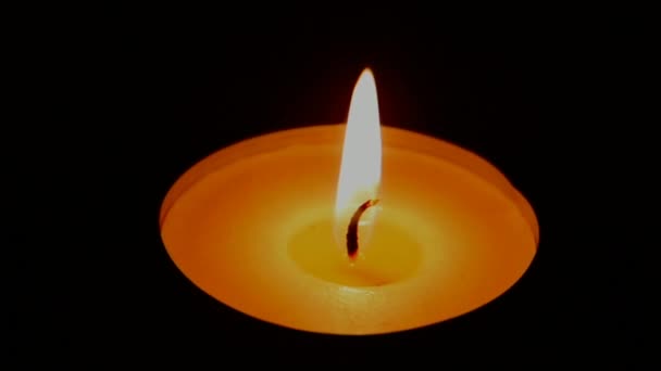 Крупный план горения свечи на фоне тёмного деревянного стола — стоковое видео